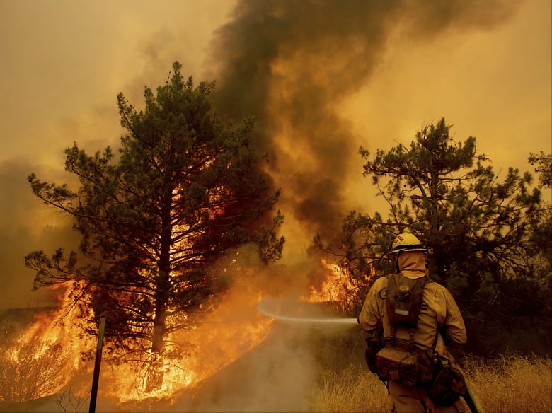 A firefighter scrambles to stop the Pawnee fire as it spots across Highway 20 near Clearlake Oaks, Calif., on Sunday, July 1, 2018.